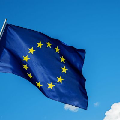 European Union EU flag waving in the wind over cloudy blue sky